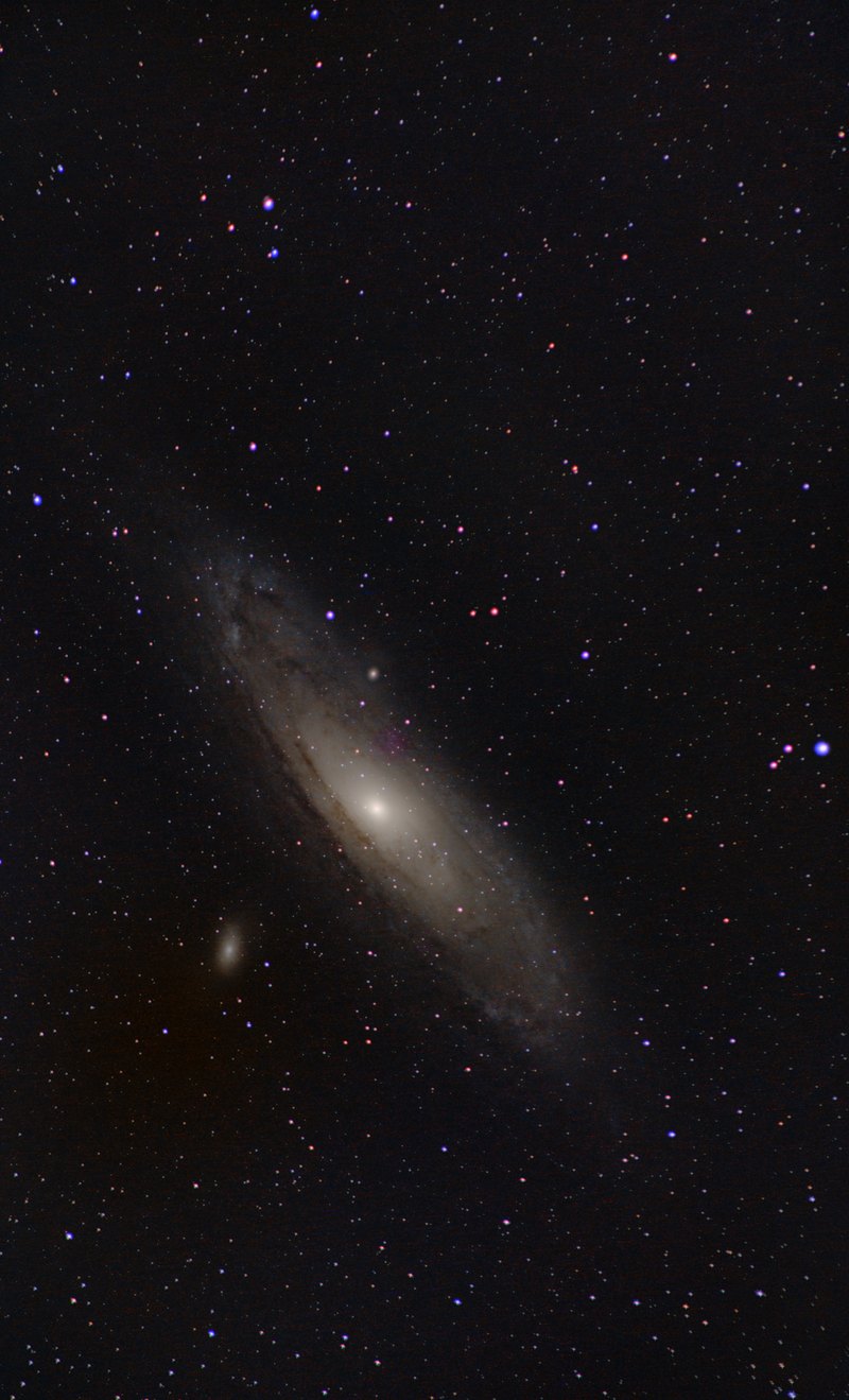 The Andromeda Galaxy as a tilted spiral among dense stars, with a small companion galaxy below it